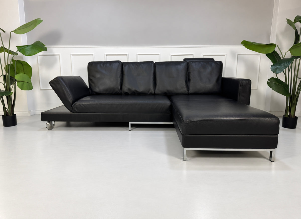 Gebrauchtes schwarzes Brühl Fourtwo Designer Leder Ecksofa vor einer Wand, stilvoll und modern eingerichtet.
