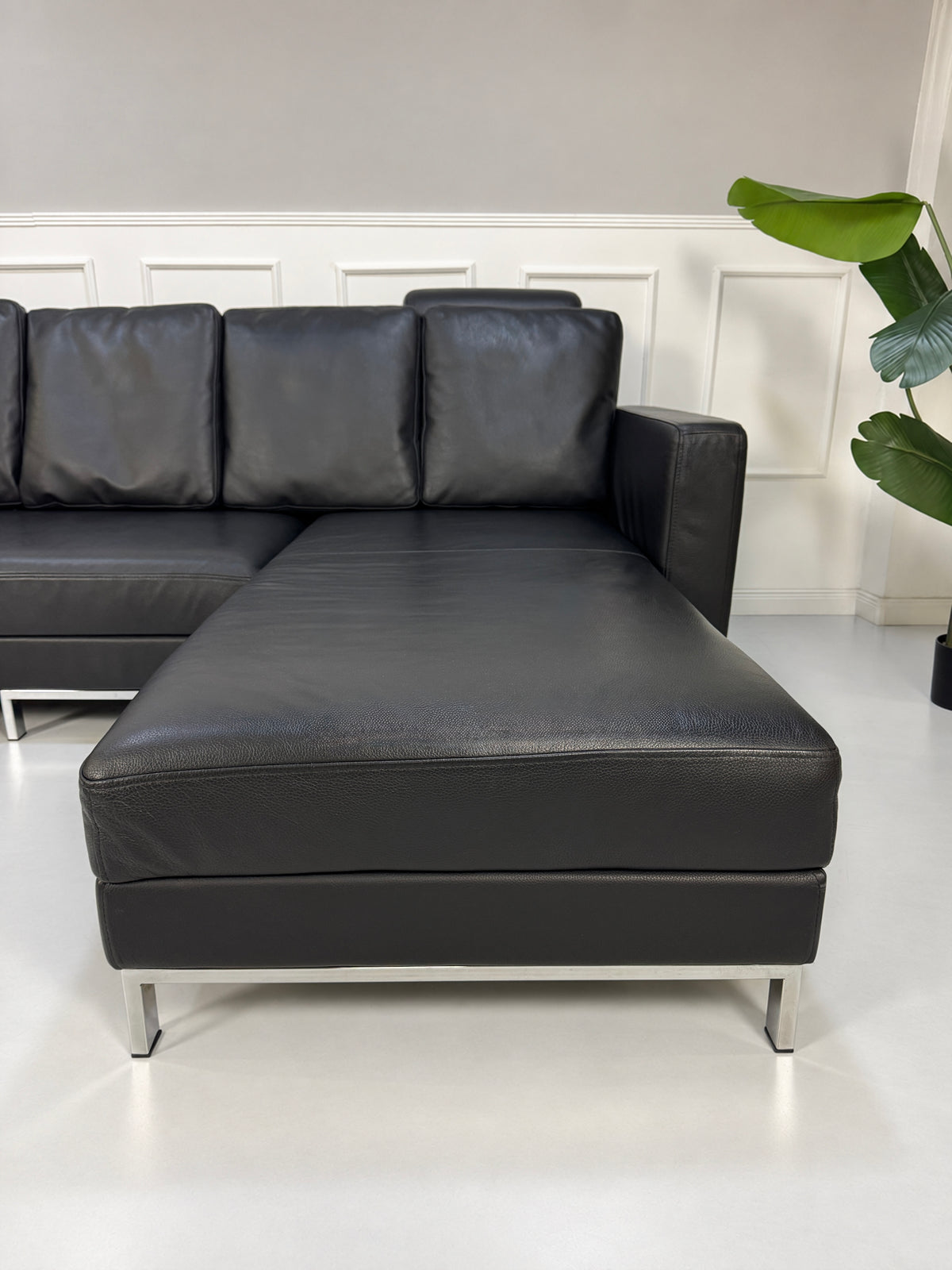 Gebrauchtes schwarzes Brühl Fourtwo Designer Leder Ecksofa vor einer Wand, stilvoll und modern eingerichtet.