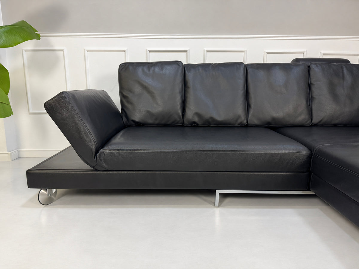 Gebrauchtes schwarzes Brühl Fourtwo Designer Leder Ecksofa vor einer Wand, stilvoll und modern eingerichtet.