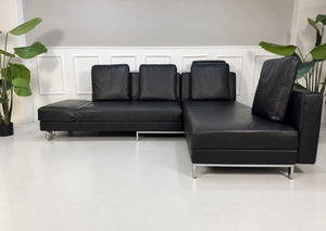 Gebrauchtes schwarzes Brühl Fourtwo Designer Leder Ecksofa vor einer Wand, stilvoll und modern eingerichtet.