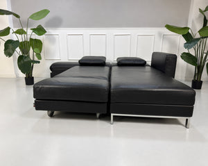 Gebrauchtes schwarzes Brühl Fourtwo Designer Leder Ecksofa vor einer Wand, stilvoll und modern eingerichtet.