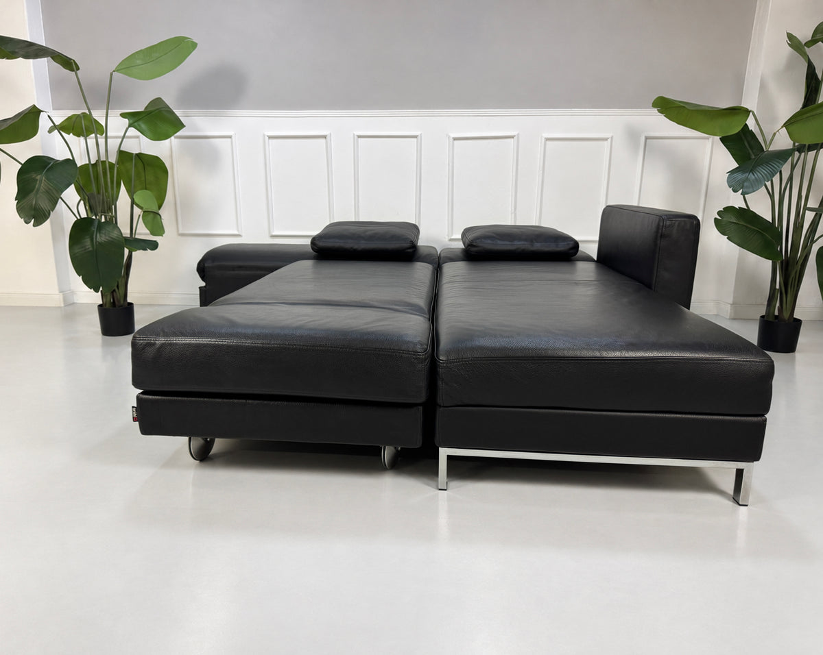 Gebrauchtes schwarzes Brühl Fourtwo Designer Leder Ecksofa vor einer Wand, stilvoll und modern eingerichtet.