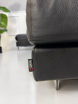 Gebrauchtes schwarzes Brühl Fourtwo Designer Leder Ecksofa vor einer Wand, stilvoll und modern eingerichtet.