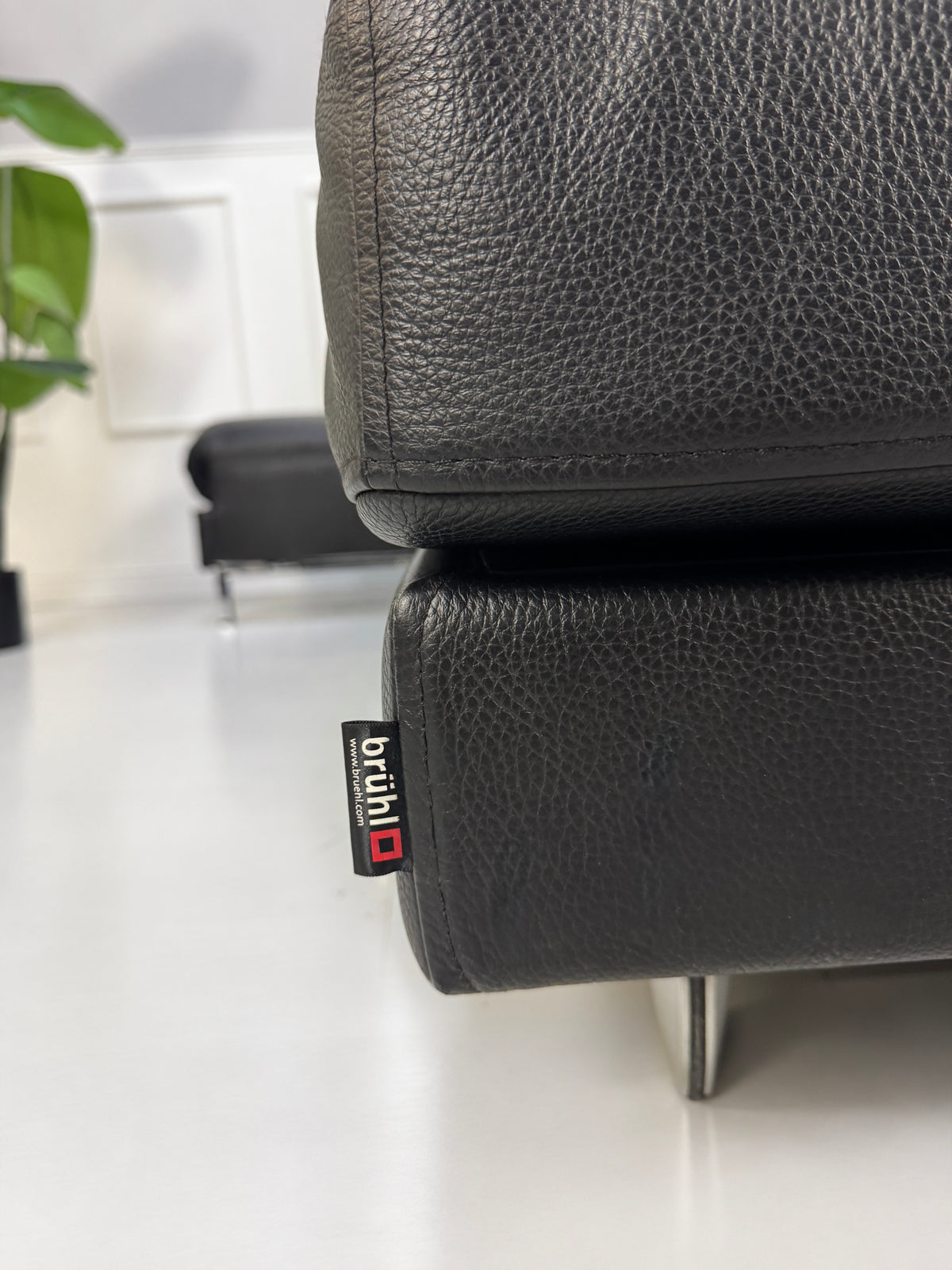 Gebrauchtes schwarzes Brühl Fourtwo Designer Leder Ecksofa vor einer Wand, stilvoll und modern eingerichtet.