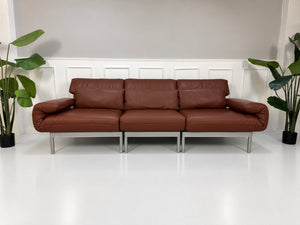 Gebrauchtes braunes Rolf Benz Plura 380 Designer Leder Sofa vor einer Wand, stilvoll und modern eingerichtet.