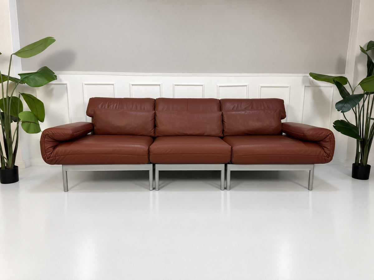 Gebrauchtes braunes Rolf Benz Plura 380 Designer Leder Sofa vor einer Wand, stilvoll und modern eingerichtet.