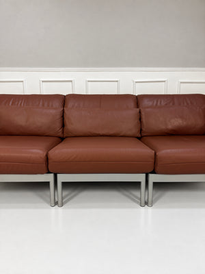 Gebrauchtes braunes Rolf Benz Plura 380 Designer Leder Sofa vor einer Wand, stilvoll und modern eingerichtet.