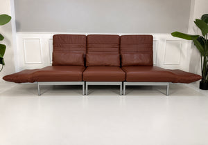 Gebrauchtes braunes Rolf Benz Plura 380 Designer Leder Sofa vor einer Wand, stilvoll und modern eingerichtet.
