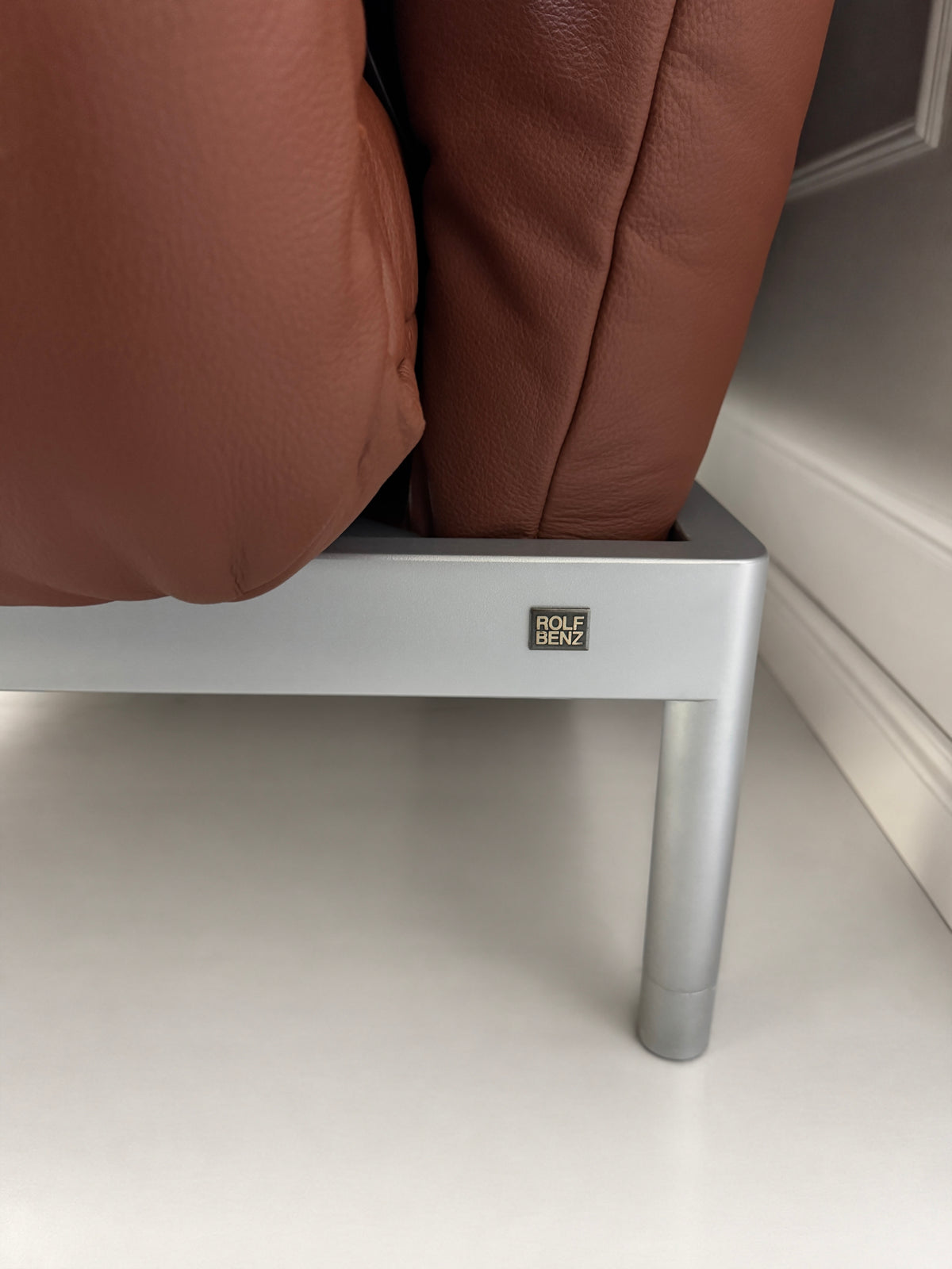 Gebrauchtes braunes Rolf Benz Plura 380 Designer Leder Sofa vor einer Wand, stilvoll und modern eingerichtet.