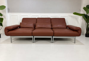 Gebrauchtes braunes Rolf Benz Plura 380 Designer Leder Sofa vor einer Wand, stilvoll und modern eingerichtet.
