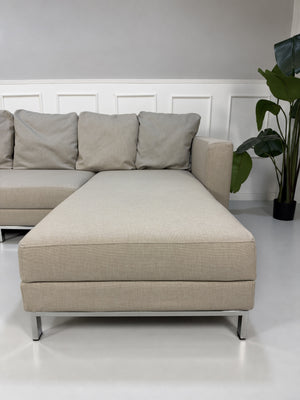 Gebrauchtes beiges Brühl Fourtwo Designer Stoff Ecksofa vor einer Wand, stilvoll und modern eingerichtet.