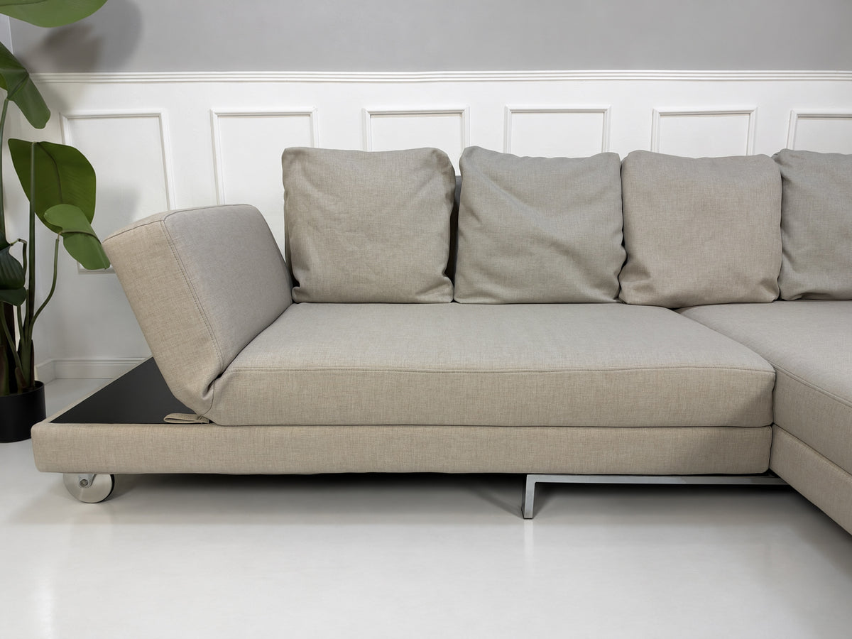 Gebrauchtes beiges Brühl Fourtwo Designer Stoff Ecksofa vor einer Wand, stilvoll und modern eingerichtet.