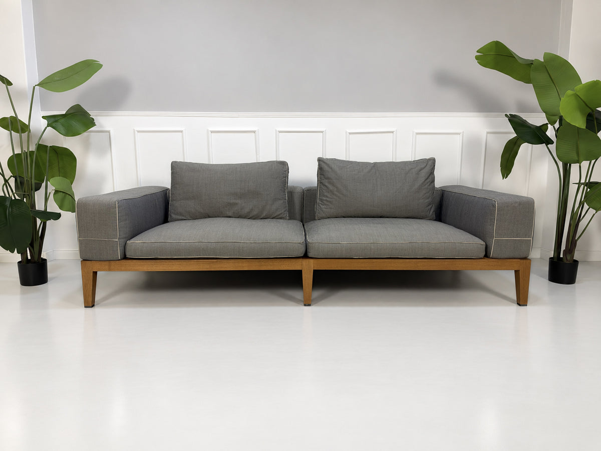 Gebrauchtes graues Flexform Lifewood Designer Stoff Sofa mit Love Chair vor einer Wand, stilvoll und modern eingerichtet.