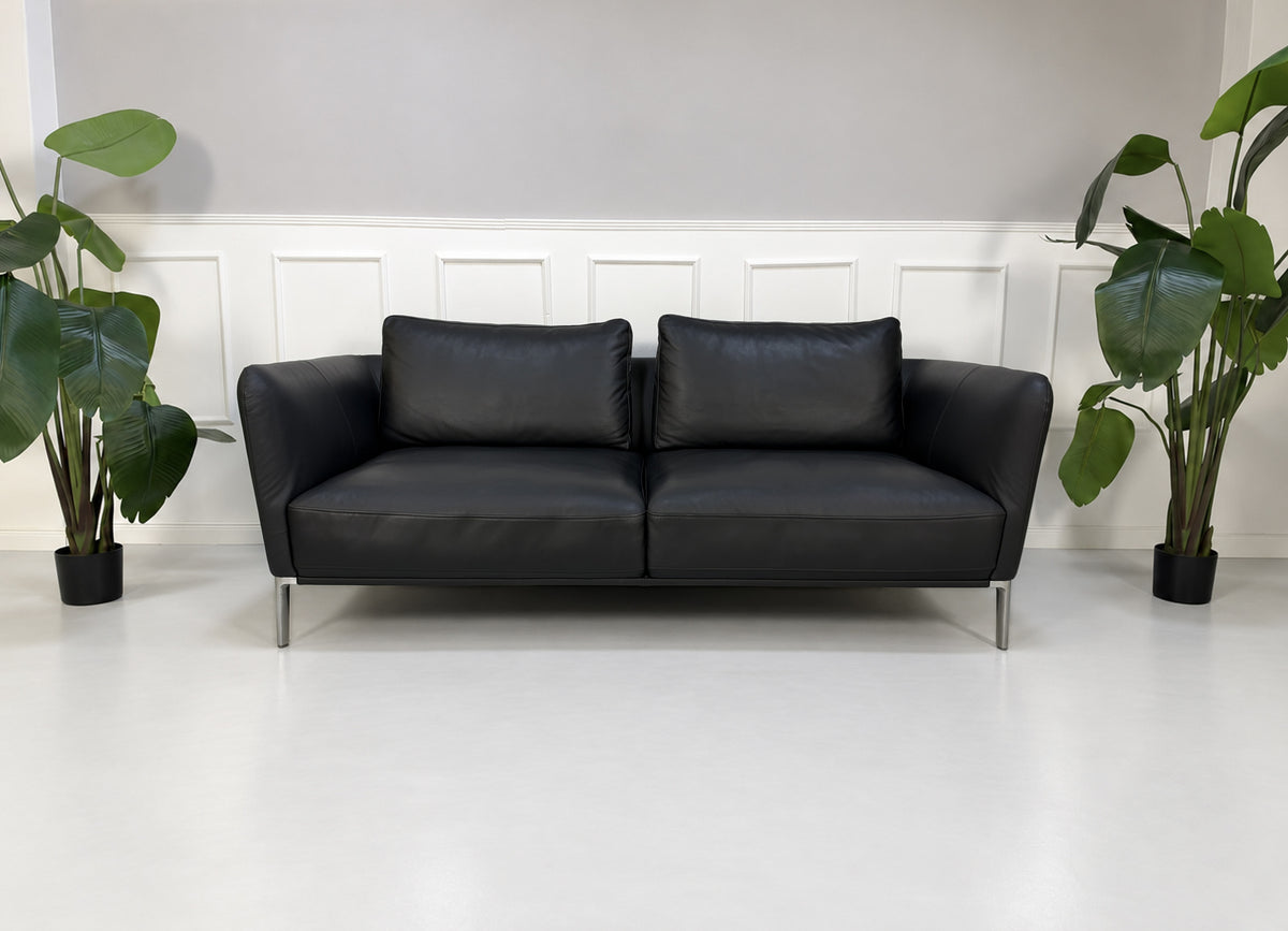 Gebrauchtes schwarzes Rolf Benz Scala Designer Leder Sofa vor einer Wand, stilvoll und modern eingerichtet.