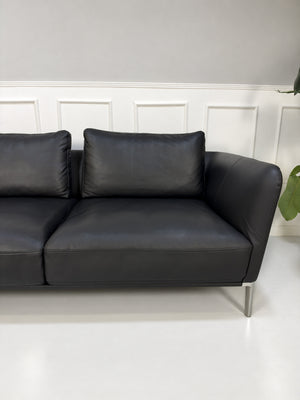 Gebrauchtes schwarzes Rolf Benz Scala Designer Leder Sofa vor einer Wand, stilvoll und modern eingerichtet.