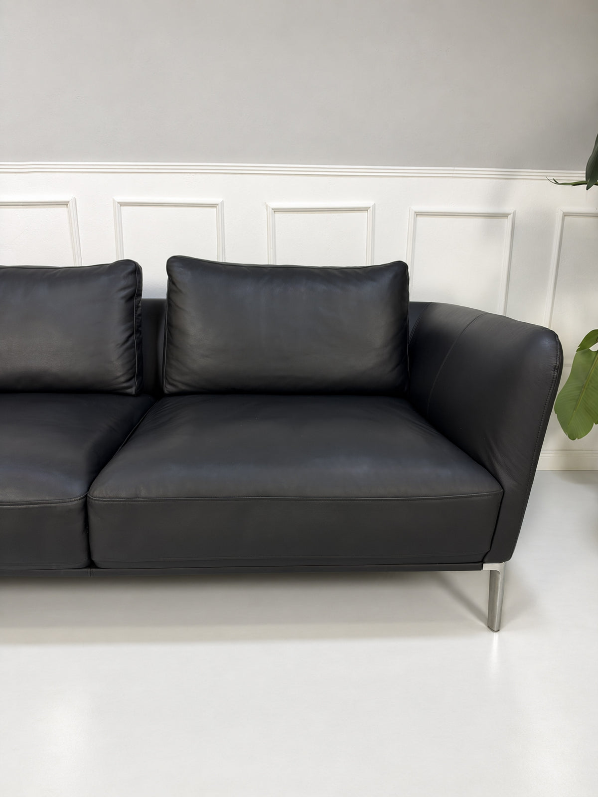 Gebrauchtes schwarzes Rolf Benz Scala Designer Leder Sofa vor einer Wand, stilvoll und modern eingerichtet.