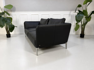 Gebrauchtes schwarzes Rolf Benz Scala Designer Leder Sofa vor einer Wand, stilvoll und modern eingerichtet.