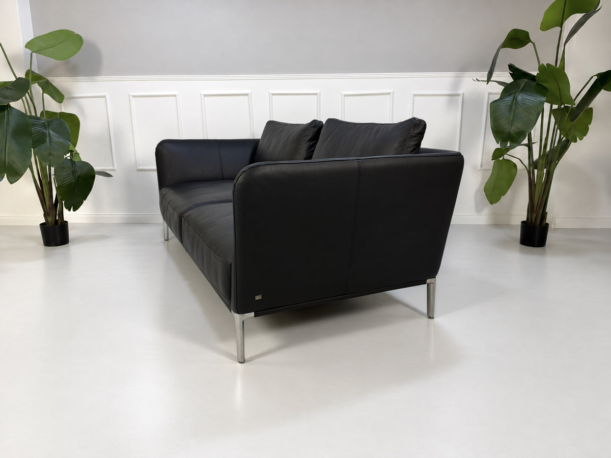 Gebrauchtes schwarzes Rolf Benz Scala Designer Leder Sofa vor einer Wand, stilvoll und modern eingerichtet.