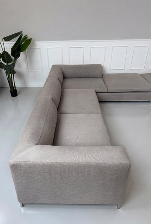 Gebrauchtes graues B&B Italia Michel Designer Stoff Sofa vor einer Wand, stilvoll und modern eingerichtet.