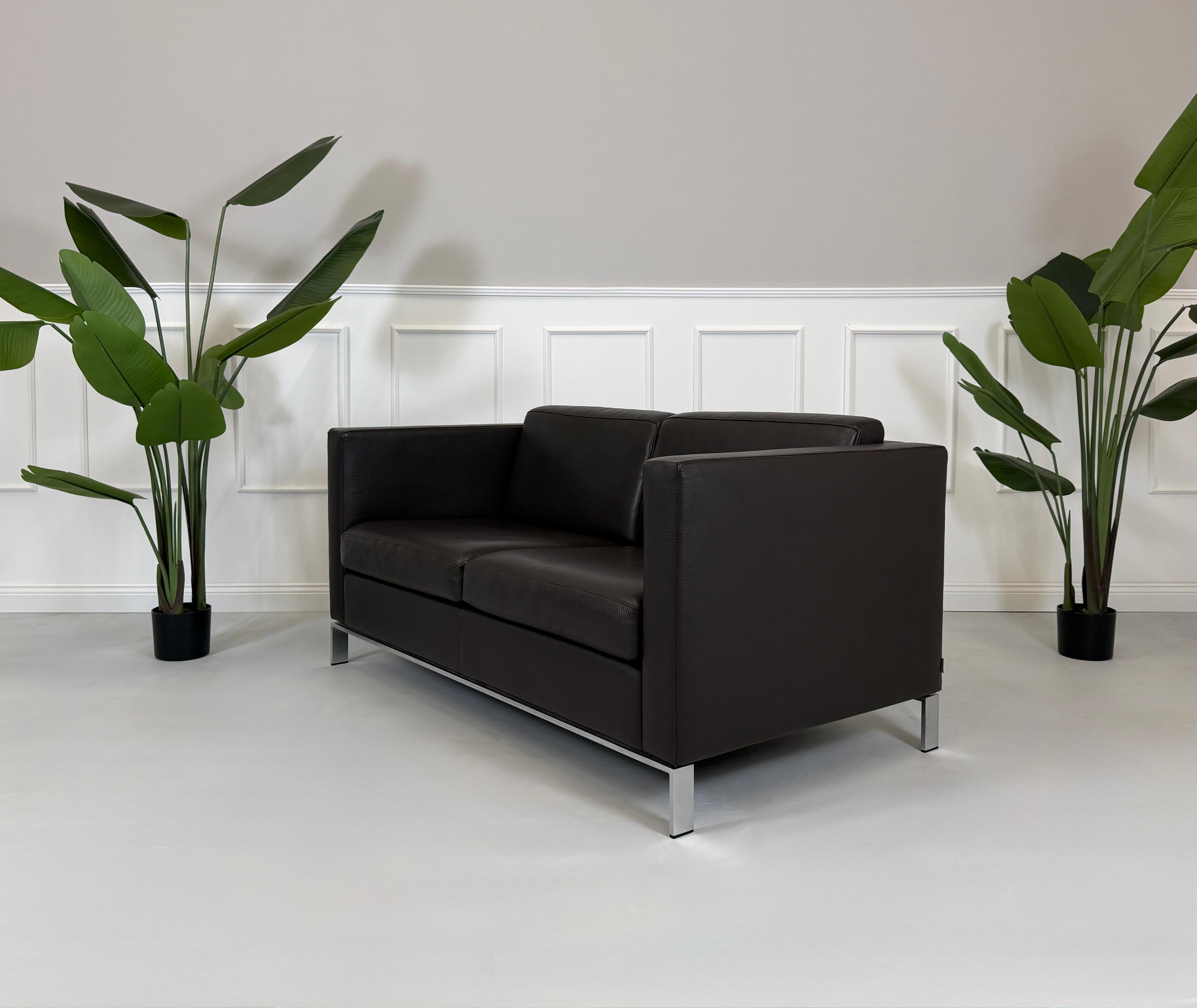 Gebrauchtes braunes Walter Knoll Foster Designer Leder Sofa vor einer Wand, stilvoll und modern eingerichtet.