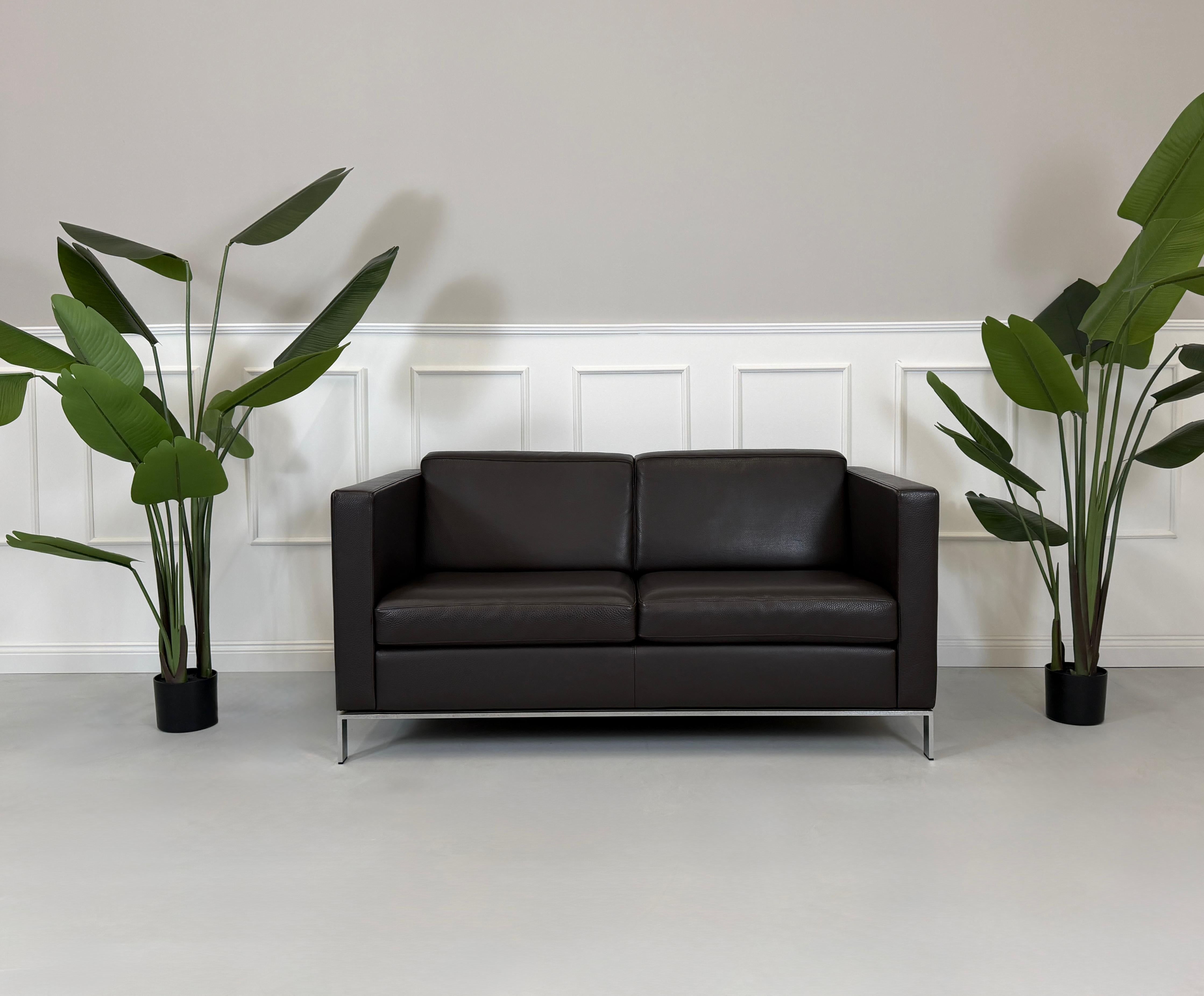 Gebrauchtes braunes Walter Knoll Foster Designer Leder Sofa vor einer Wand, stilvoll und modern eingerichtet.