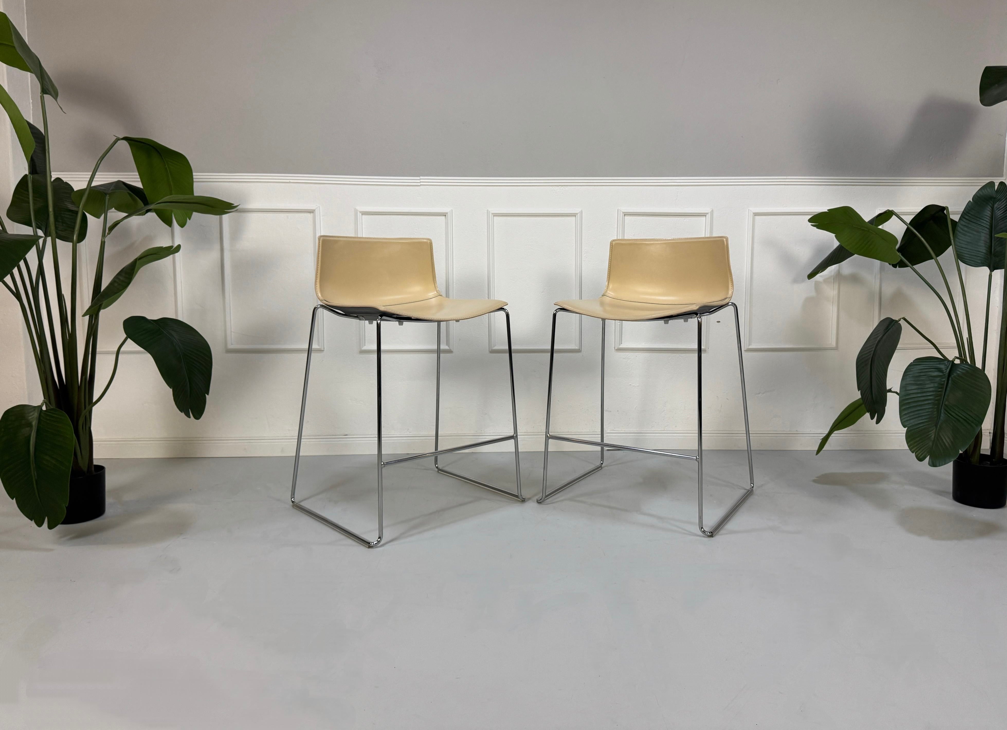Gebrauchte beige Arper Catifa Designer Leder Stühle Barhocker vor einer Wand, stilvoll und modern eingerichtet.