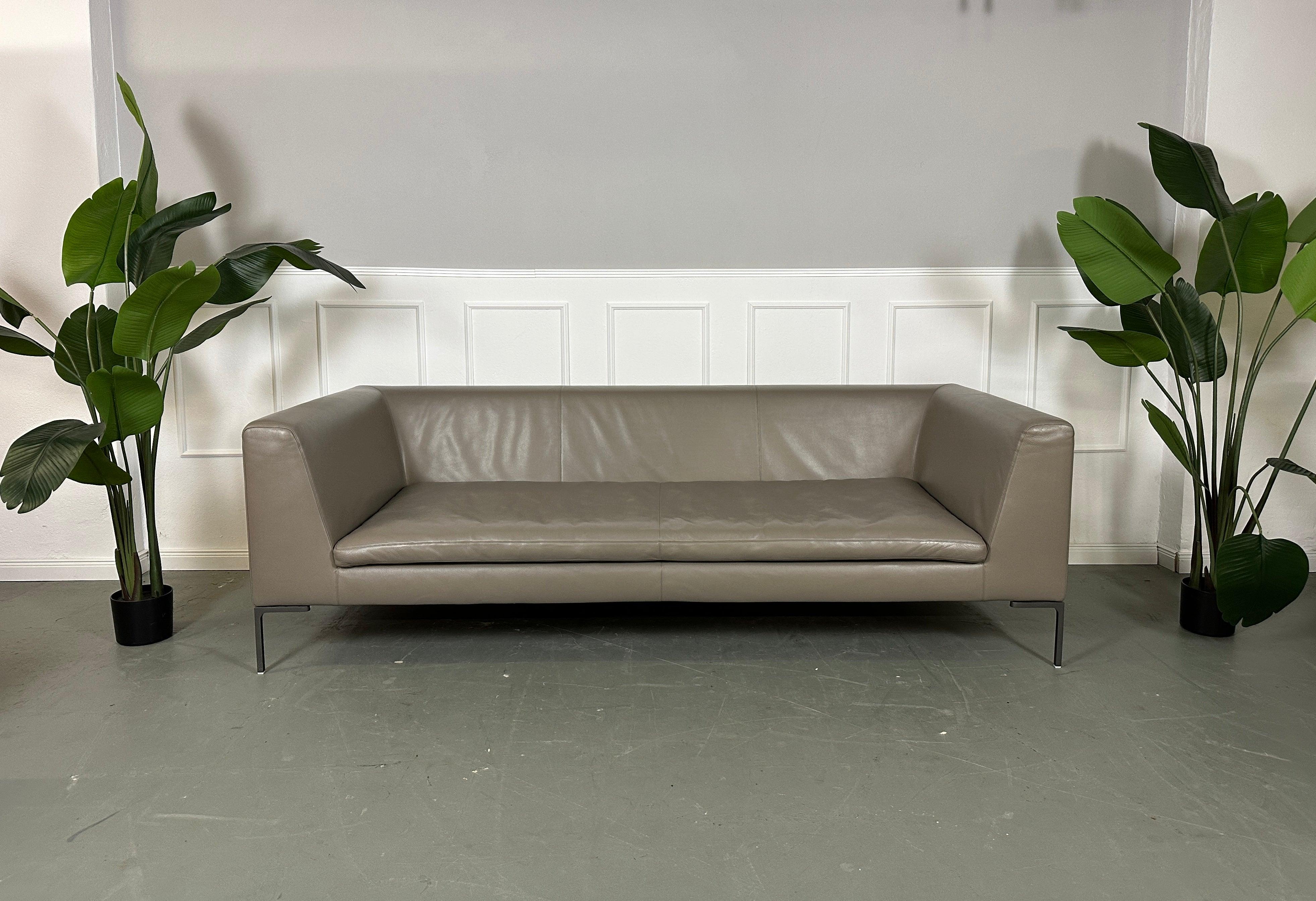 Gebrauchtes B&B Italia Charles Designer Leder Sofa plus Hocker vor einer Wand, stilvoll und modern eingerichtet.