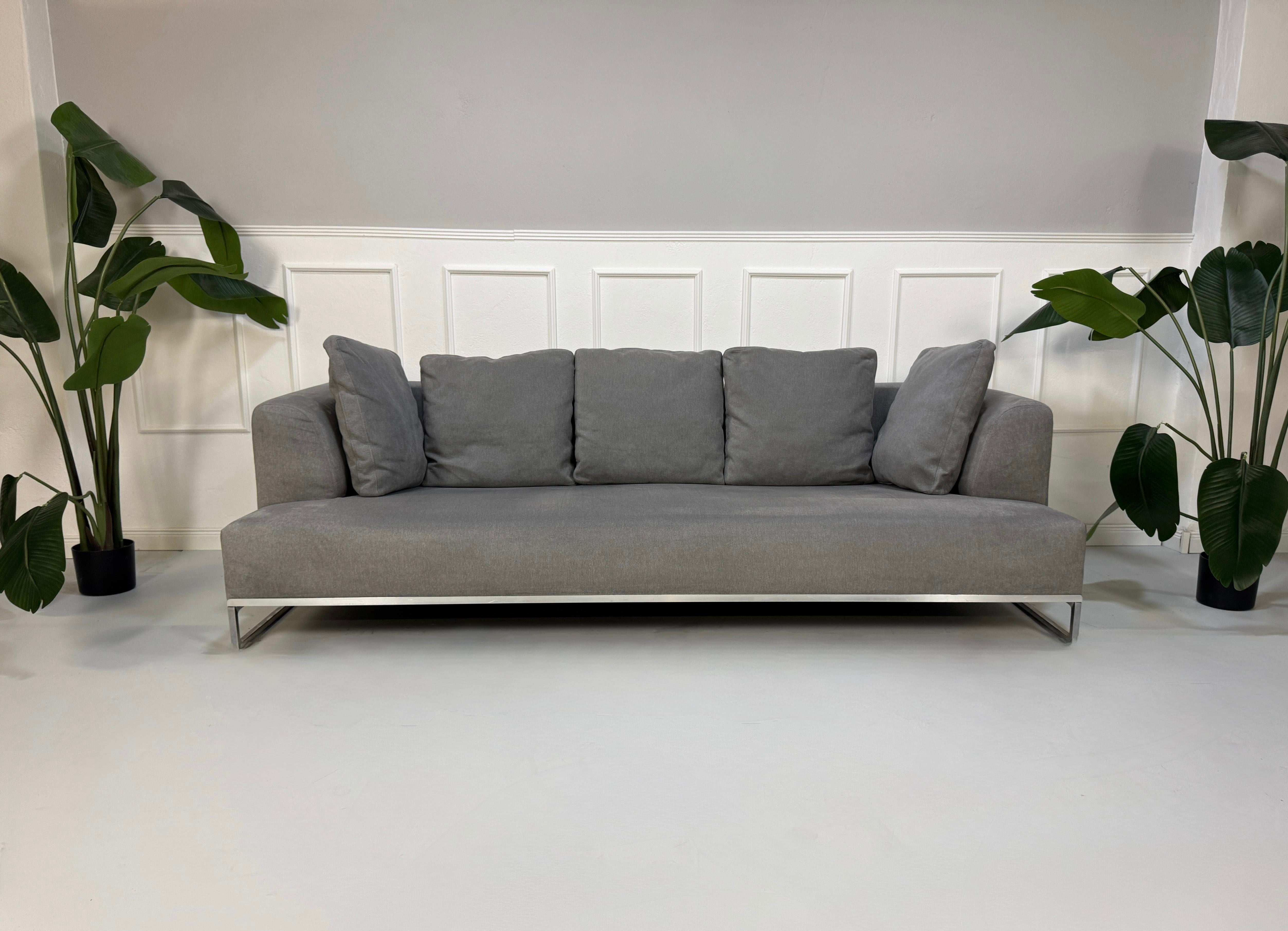 Gebrauchtes graues BB Italia Solo Designer Stoff Sofa mit Tavalo Tisch und Hocker vor einer Wand, stilvoll und modern eingerichtet.