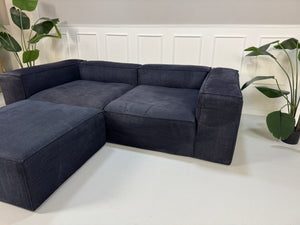 Gebrauchtes blaues Bolia Cosima Designer Stoff Sofa vor einer Wand, stilvoll und modern eingerichtet.