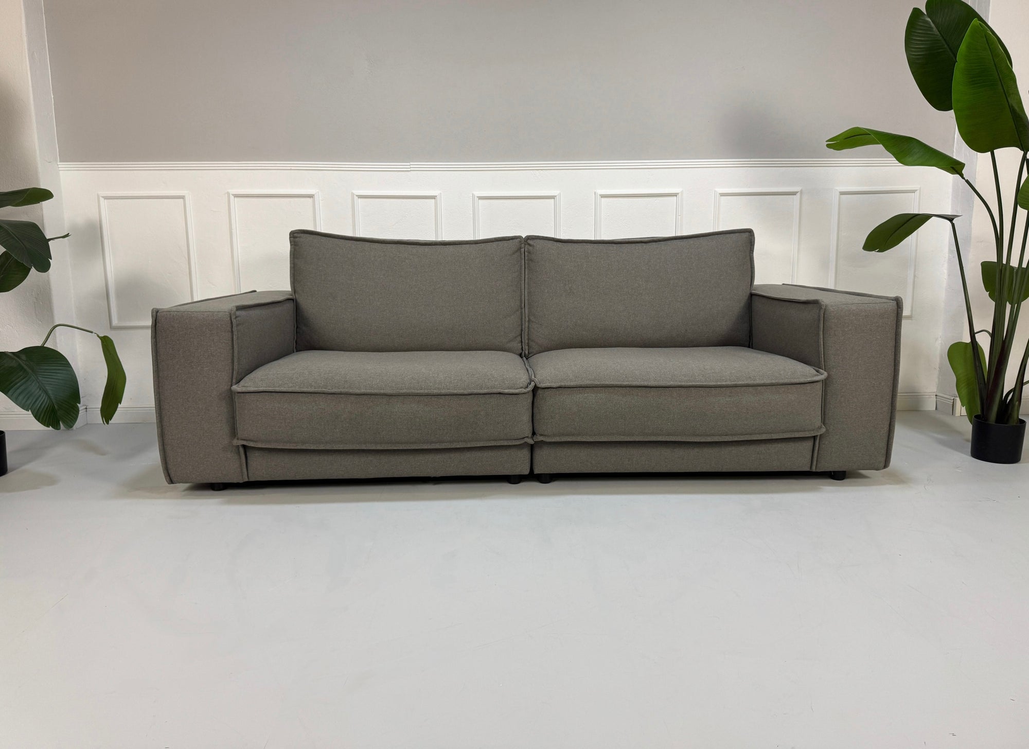 Gebrauchtes graues Bolia Noora Designer Stoff Sofa vor einer Wand, stilvoll und modern eingerichtet.
