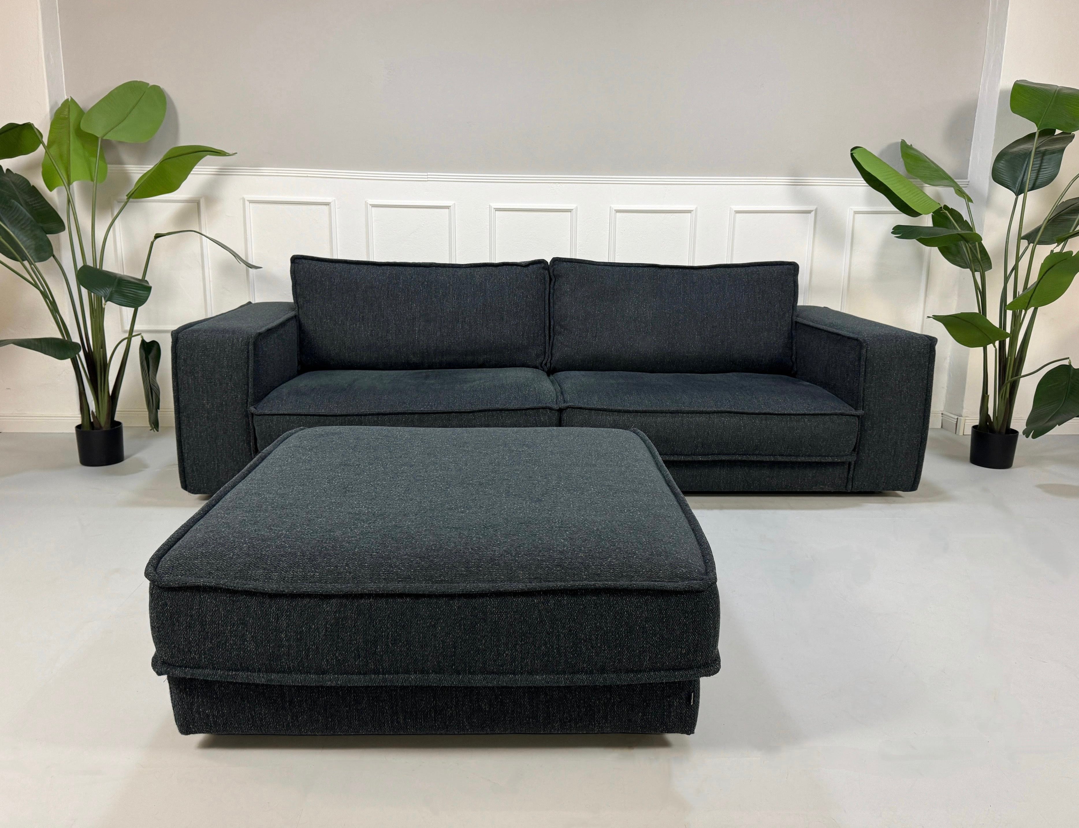 Gebrauchtes blaues Bolia Noora Designer Stoff Sofa vor einer Wand, stilvoll und modern eingerichtet.