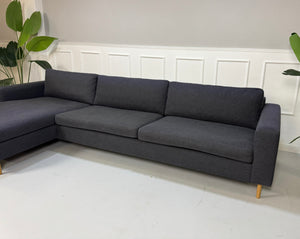 Gebrauchtes lila Bolia Scandinavia Designer Stoff Sofa vor einer Wand, stilvoll und modern eingerichtet.