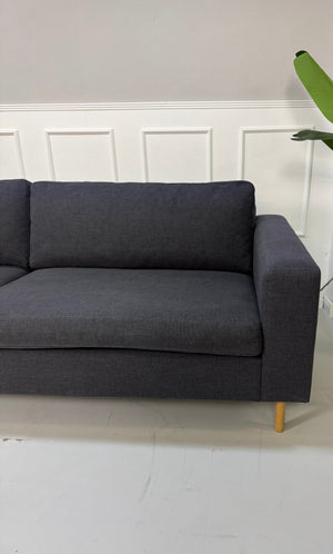 Gebrauchtes lila Bolia Scandinavia Designer Stoff Sofa vor einer Wand, stilvoll und modern eingerichtet.