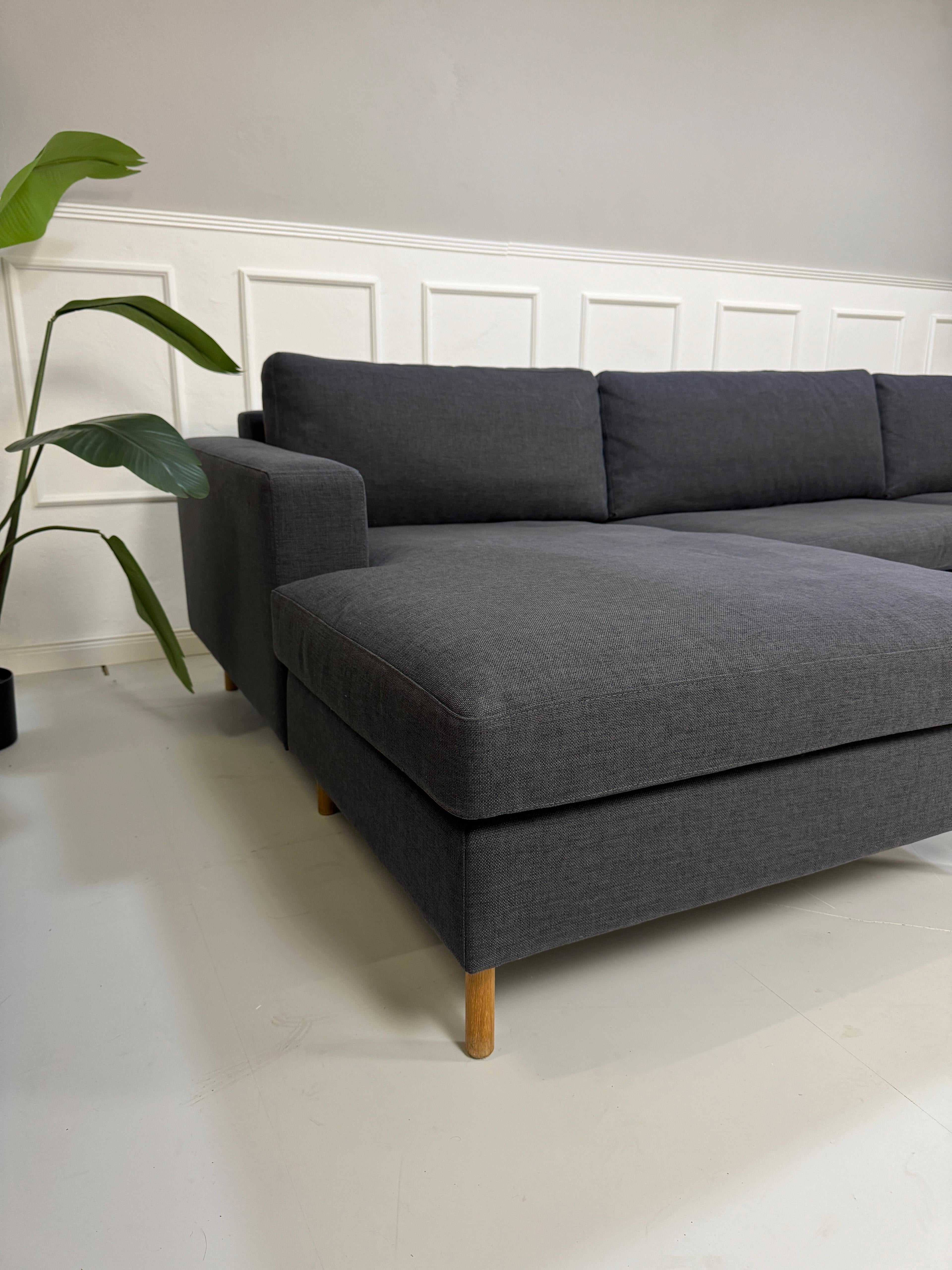 Gebrauchtes lila Bolia Scandinavia Designer Stoff Sofa vor einer Wand, stilvoll und modern eingerichtet.