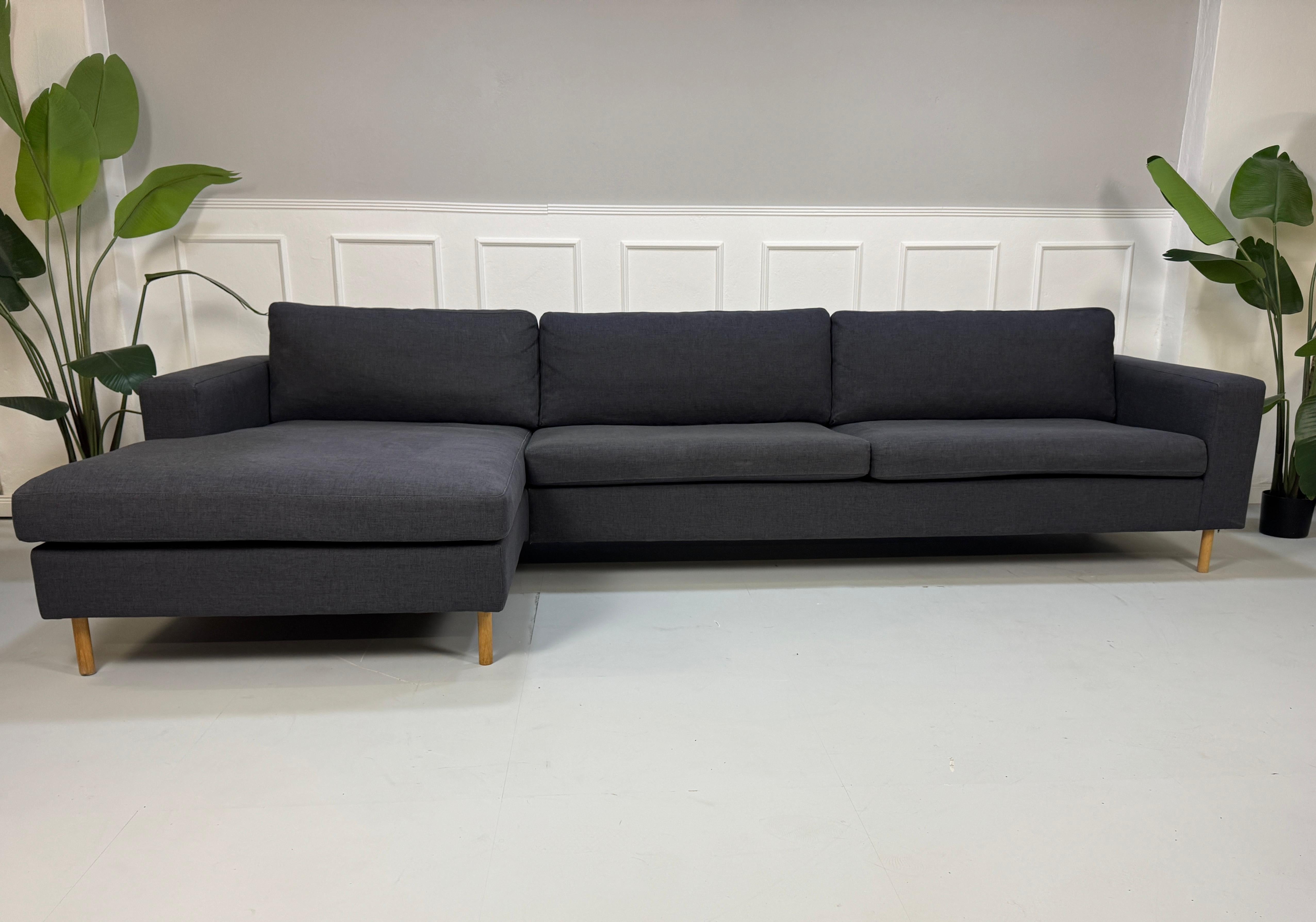 Gebrauchtes lila Bolia Scandinavia Designer Stoff Sofa vor einer Wand, stilvoll und modern eingerichtet.