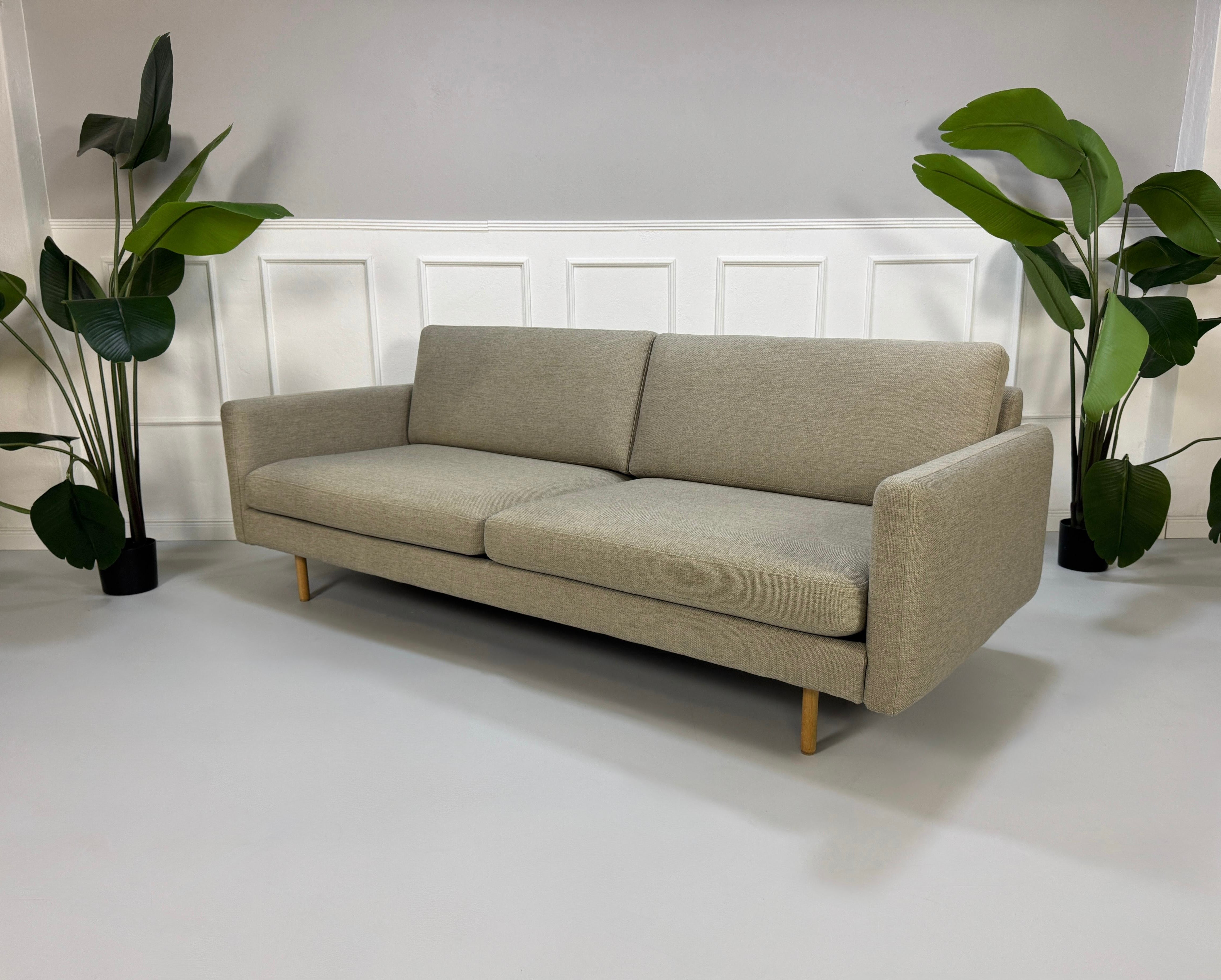 Gebrauchtes graues Bolia Remix Designer Stoff Sofa vor einer Wand, stilvoll und modern eingerichtet.