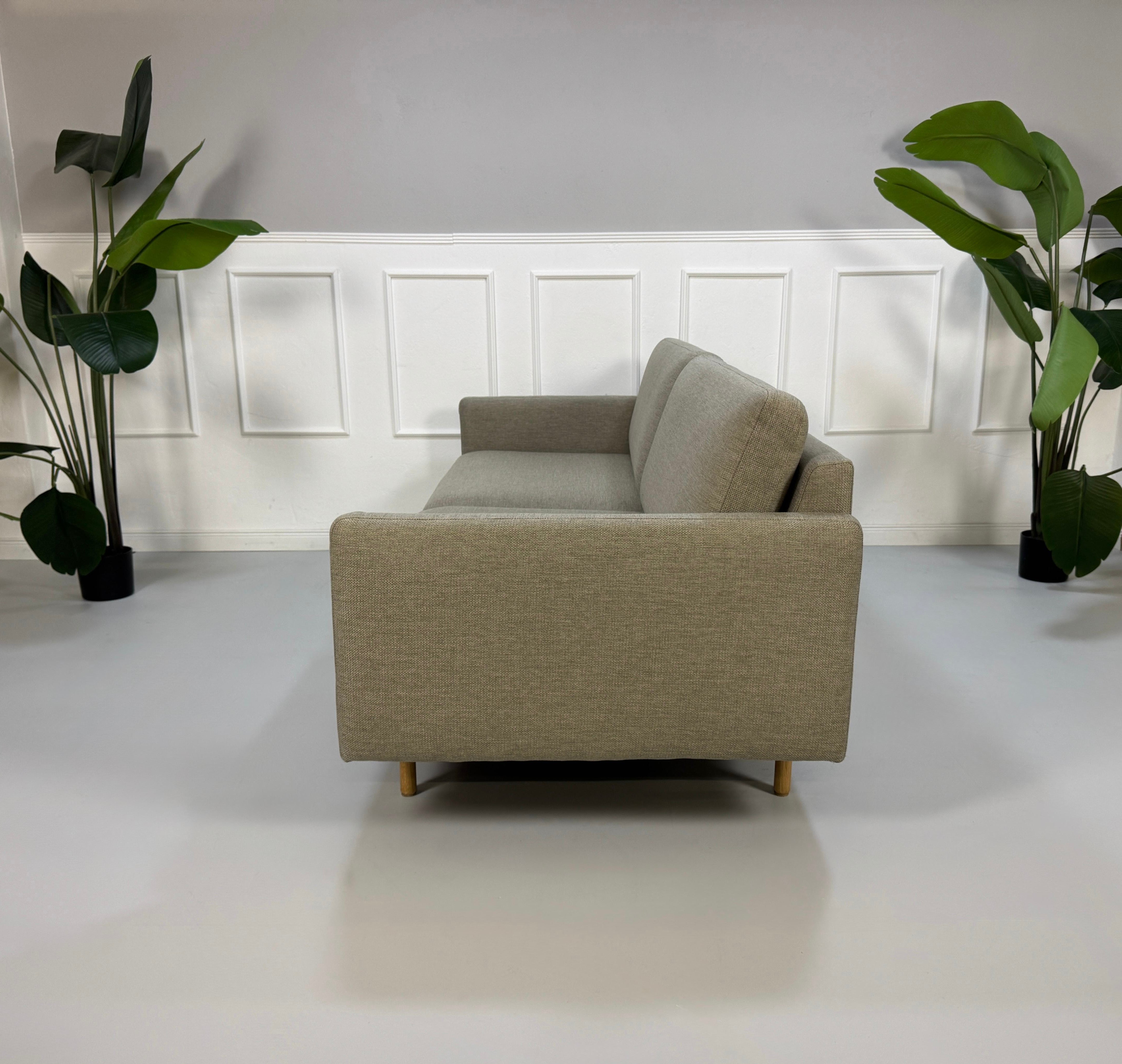 Gebrauchtes graues Bolia Remix Designer Stoff Sofa vor einer Wand, stilvoll und modern eingerichtet.