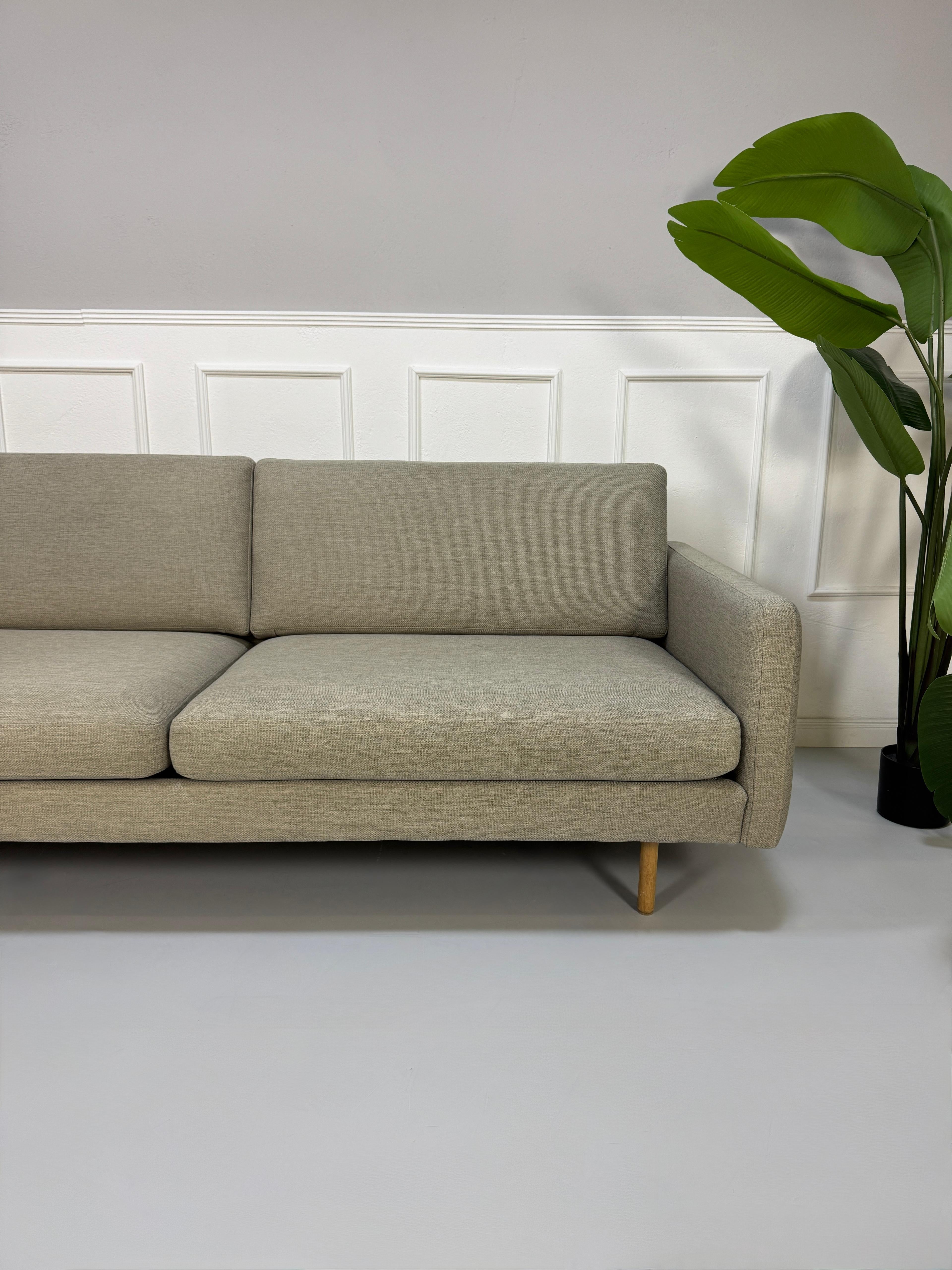Gebrauchtes graues Bolia Remix Designer Stoff Sofa vor einer Wand, stilvoll und modern eingerichtet.