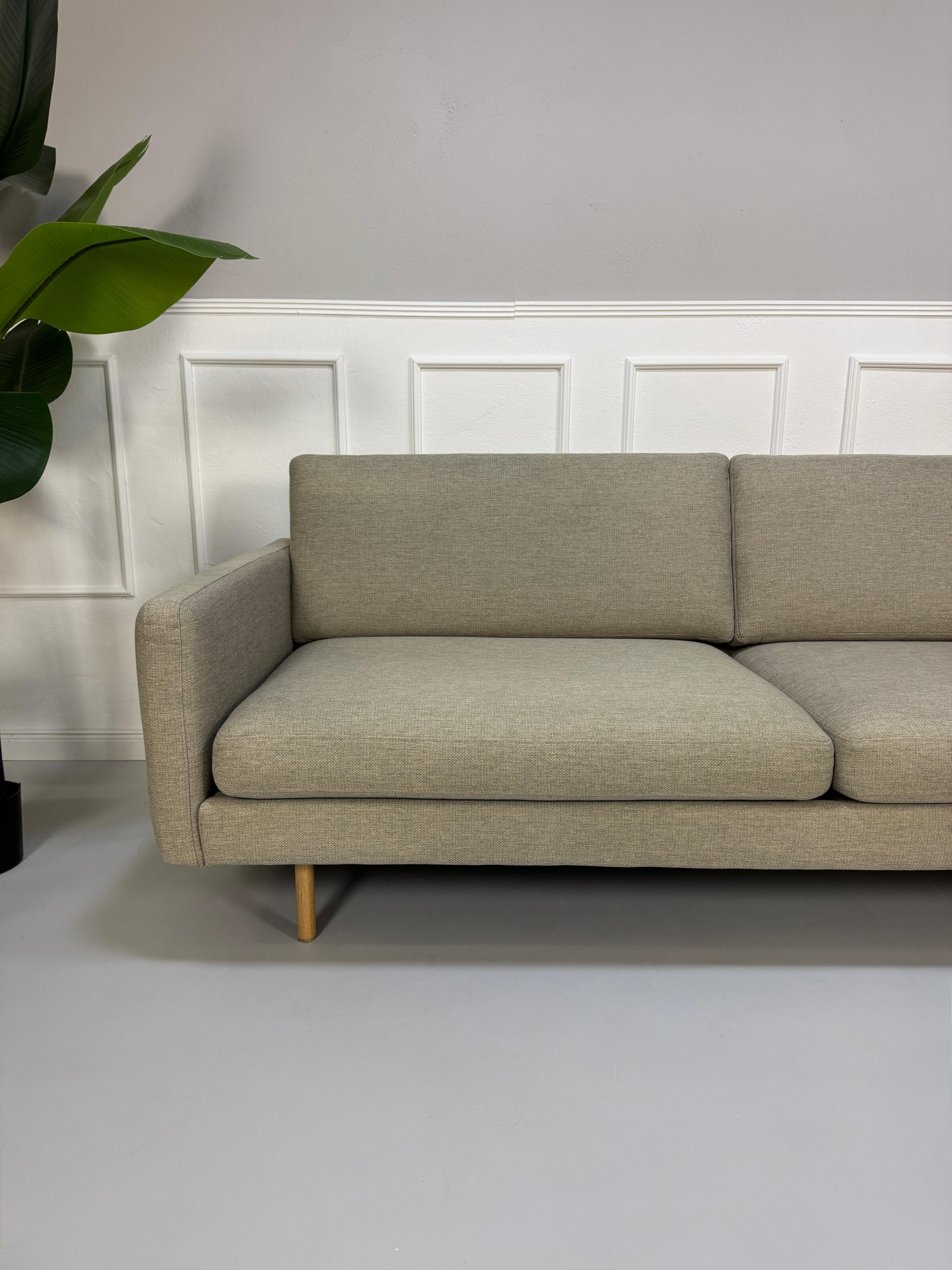 Gebrauchtes graues Bolia Remix Designer Stoff Sofa vor einer Wand, stilvoll und modern eingerichtet.