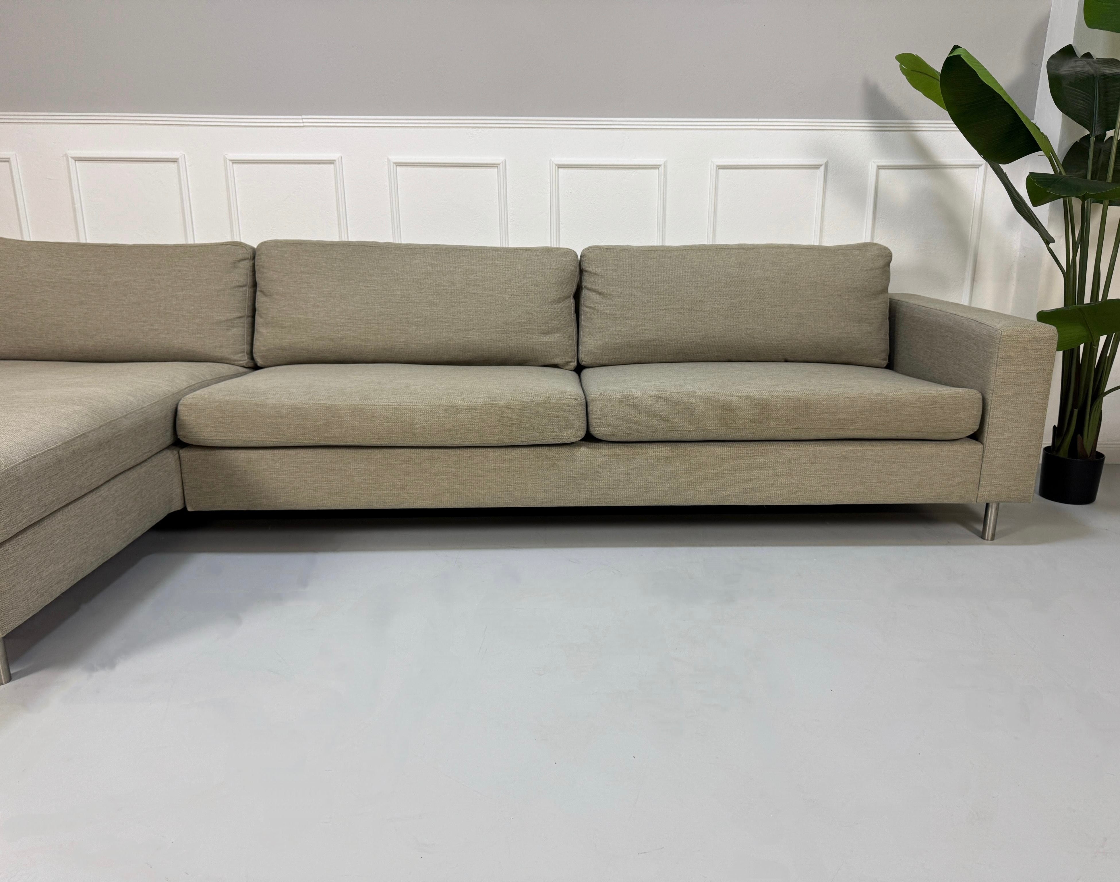 Gebrauchtes graues Bolia Scandinavia 4 Sitzer Designer Stoff Sofa vor einer Wand, stilvoll und modern eingerichtet.