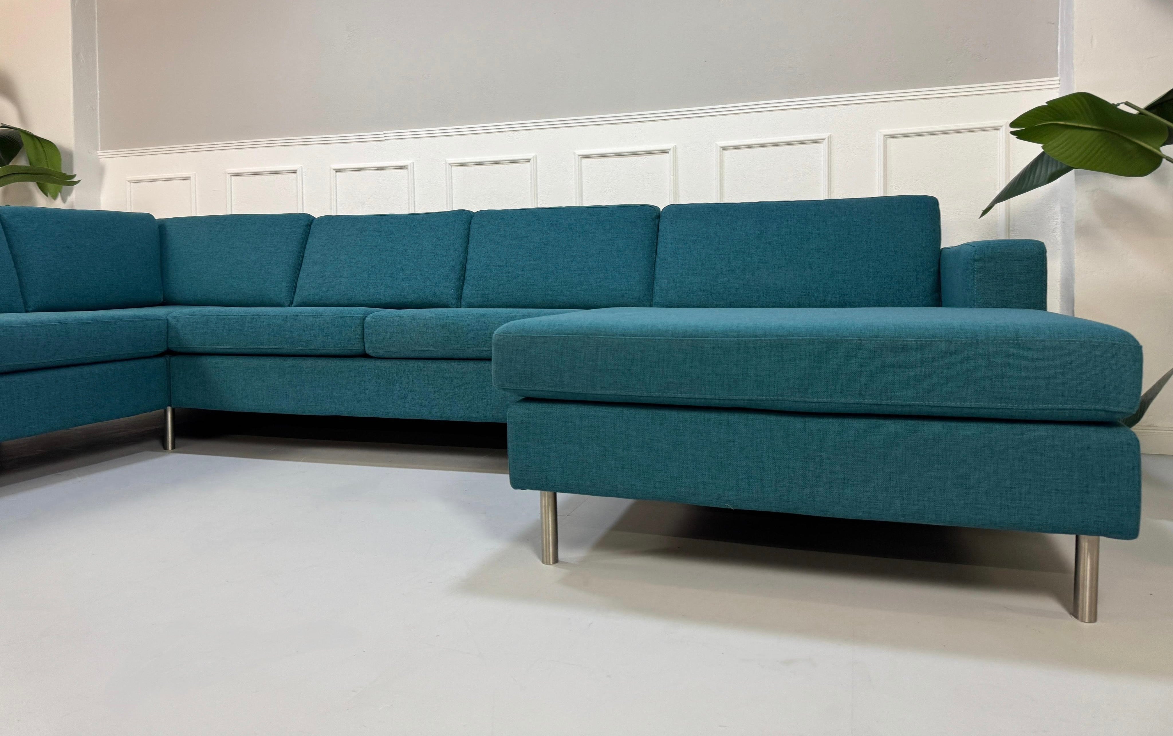 Gebrauchtes türkis Bolia Scandinavia Designer Stoff Sofa vor einer Wand, stilvoll und modern eingerichtet.