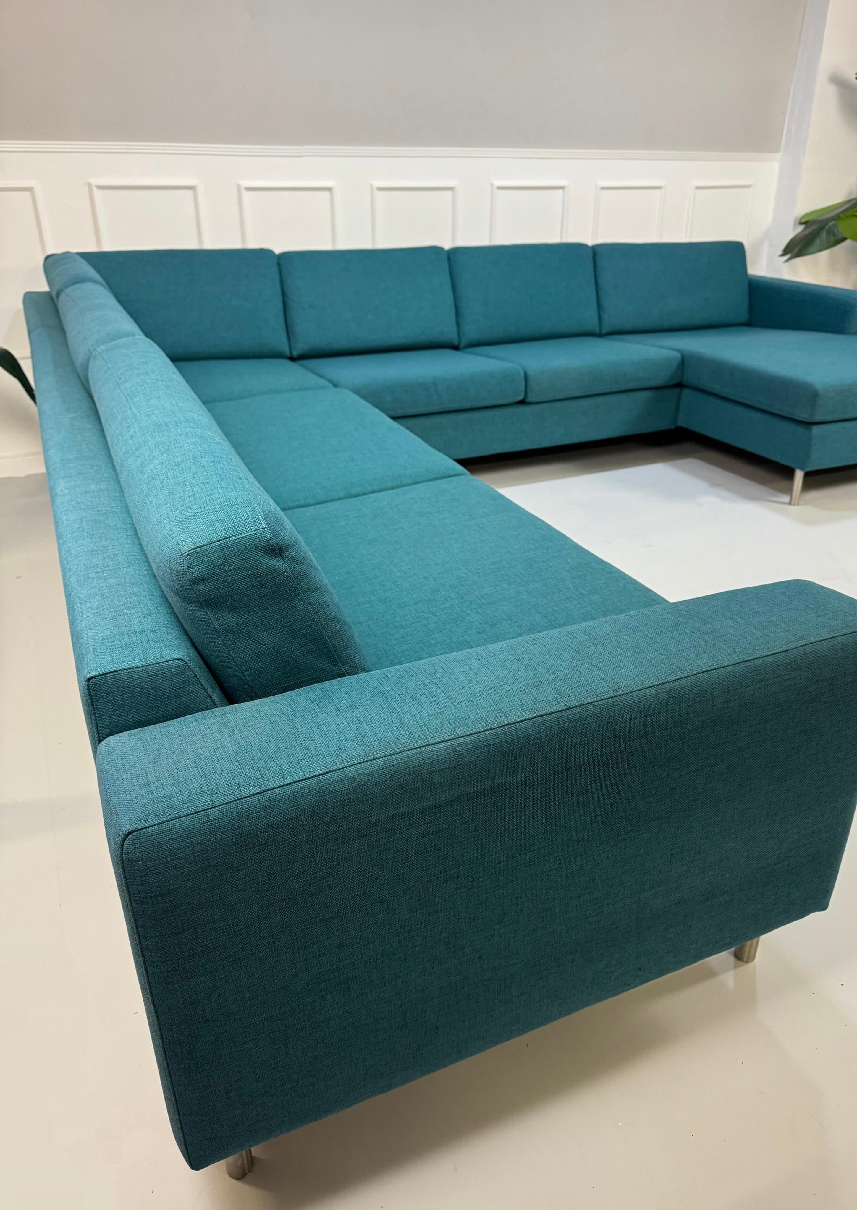 Gebrauchtes türkis Bolia Scandinavia Designer Stoff Sofa vor einer Wand, stilvoll und modern eingerichtet.