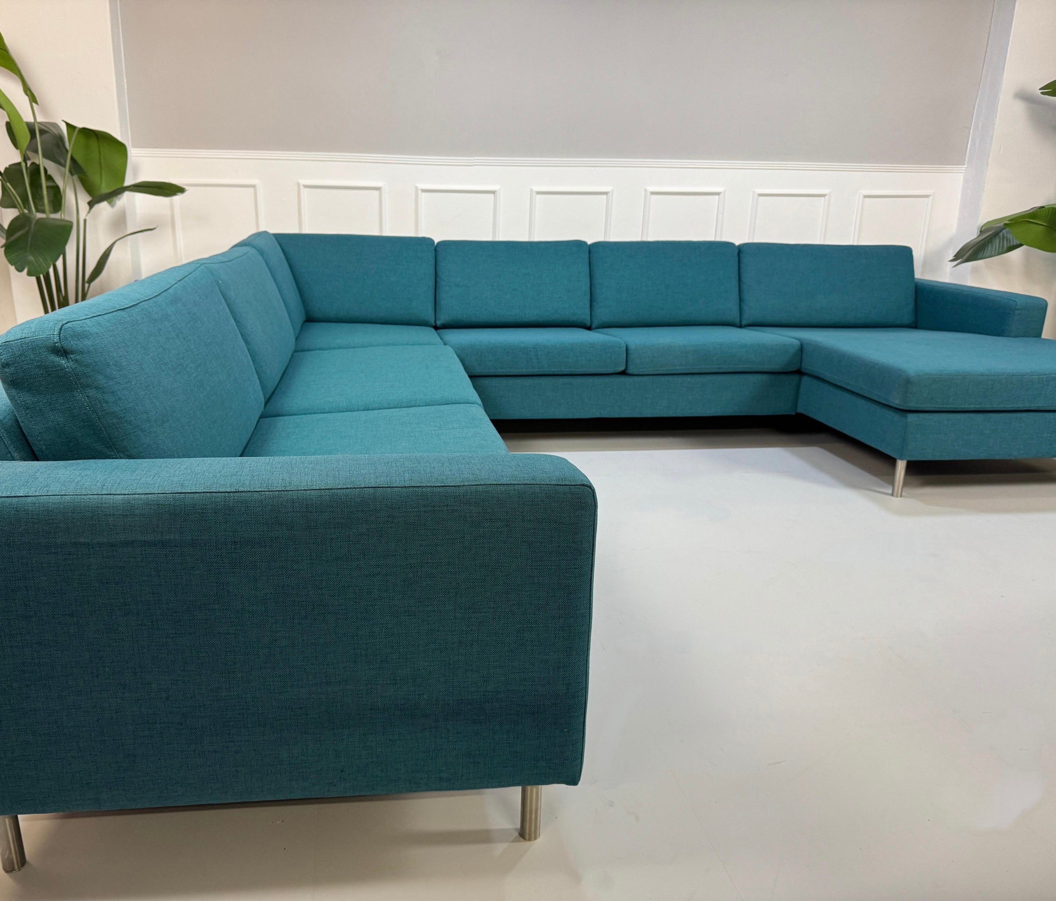 Gebrauchtes türkis Bolia Scandinavia Designer Stoff Sofa vor einer Wand, stilvoll und modern eingerichtet.