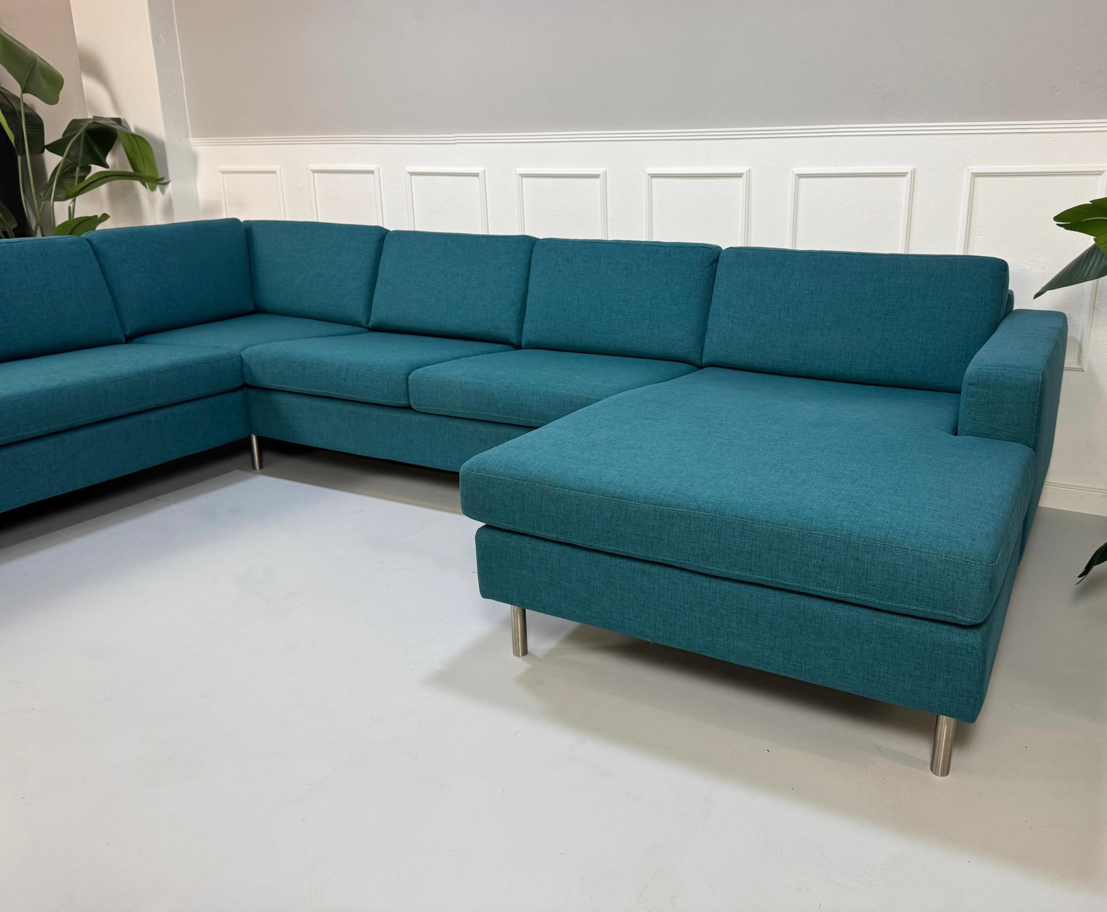 Gebrauchtes türkis Bolia Scandinavia Designer Stoff Sofa vor einer Wand, stilvoll und modern eingerichtet.