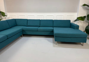 Gebrauchtes türkis Bolia Scandinavia Designer Stoff Sofa vor einer Wand, stilvoll und modern eingerichtet.