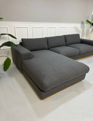 Gebrauchtes graues Bolia Sepia Designer Stoff Sofa vor einer Wand, stilvoll und modern eingerichtet.