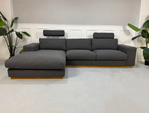 Gebrauchtes graues Bolia Sepia Designer Stoff Sofa vor einer Wand, stilvoll und modern eingerichtet.