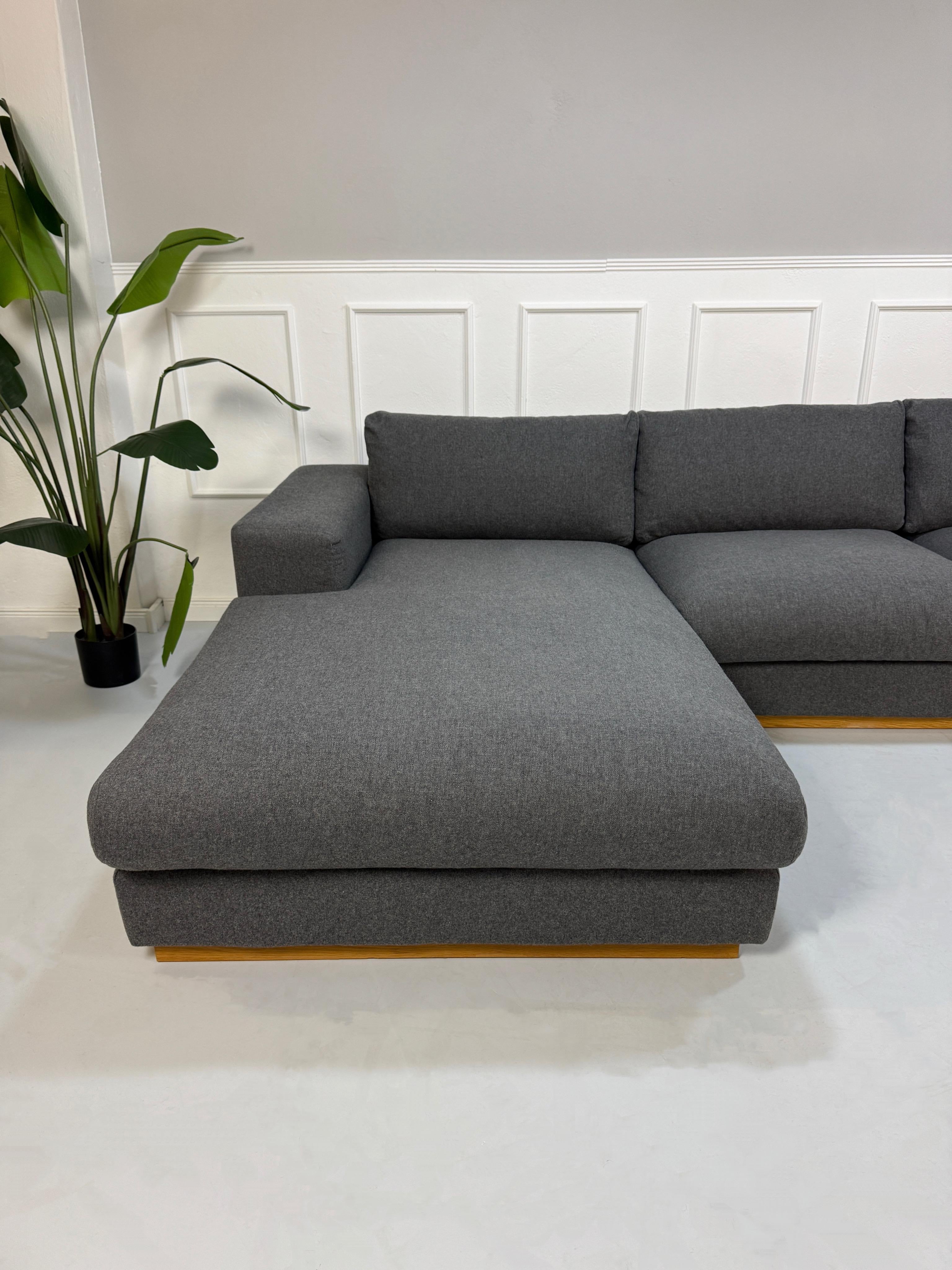 Gebrauchtes graues Bolia Sepia Designer Stoff Sofa vor einer Wand, stilvoll und modern eingerichtet.