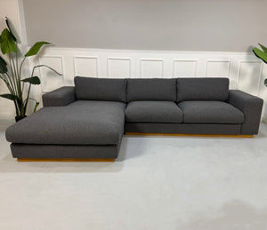 Gebrauchtes graues Bolia Sepia Designer Stoff Sofa vor einer Wand, stilvoll und modern eingerichtet.