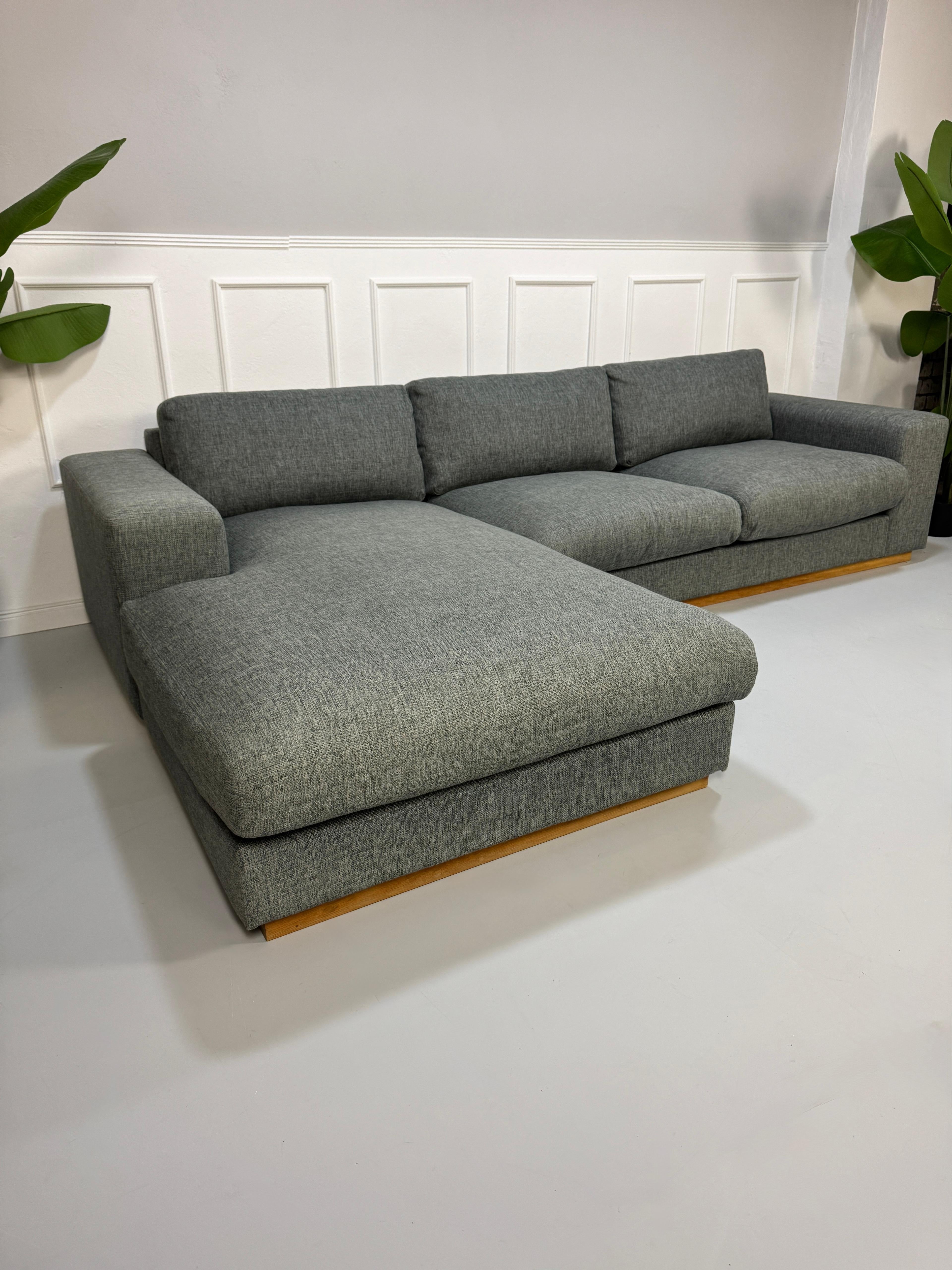 Refurbished graues Bolia Sepia Designer Stoff Sofa vor einer Wand, stilvoll und modern eingerichtet.